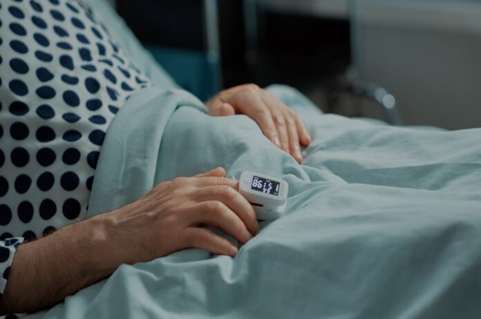 Close up of oximeter on patient in hospital ward bed